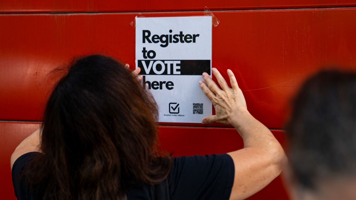 A volunteer from Brooklyn Voters Alliance posts a sign notifying people to register to vote September 27, 2020 in New York City.