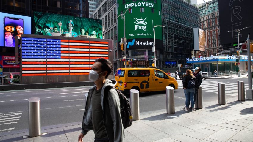 Pedestrians wearing protective masks walk past the Nasdaq MarketSite in New York, U.S., on Friday, Oct. 2, 2020. New York faced pressure as middle and high schools reopened, infection rates in virus hot spots rose further and the city's bond rating was cut by Moody's. Photographer: Michael Nagle/Bloomberg via Getty Images