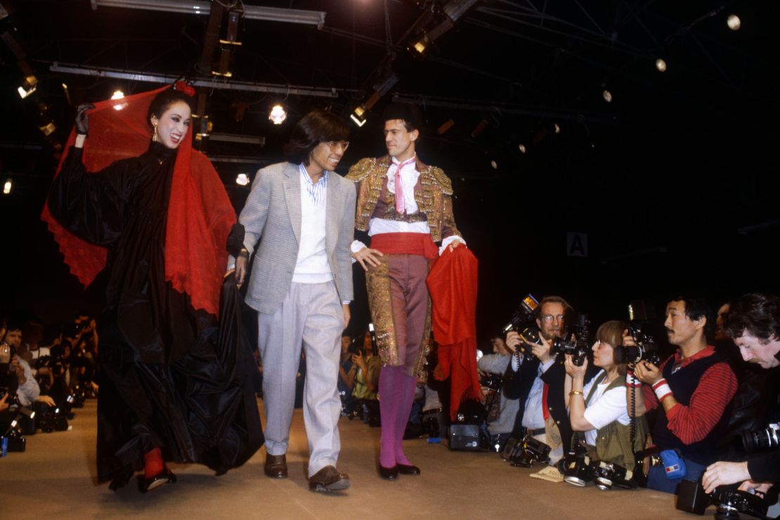 The designer accompanied by two models down his Autumn-Winter runway in Paris, 1983.
