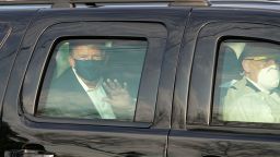 US President Trump waves from the back of a car in a motorcade outside of Walter Reed Medical Center in Bethesda, Maryland on October 4, 2020.