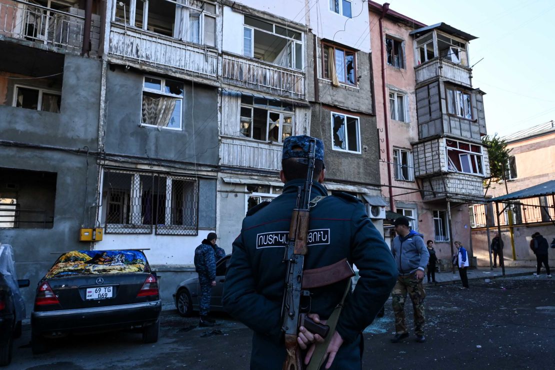 A police officer stands in front of a damaged apartment building in Stepanakert, during the ongoing conflict.