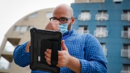 Joseph Ortiz, a contact tracer with New York City's Health + Hospitals battling the coronavirus pandemic, uses his tablet to gather information as he heads to a potential patient's home Thursday, Aug. 6, 2020, in New York. The city has hired more than 3,000 tracers and the city says it's now meeting its goal of reaching about 90% of all newly diagnosed people and completing interviews with 75%. (AP Photo/John Minchillo)