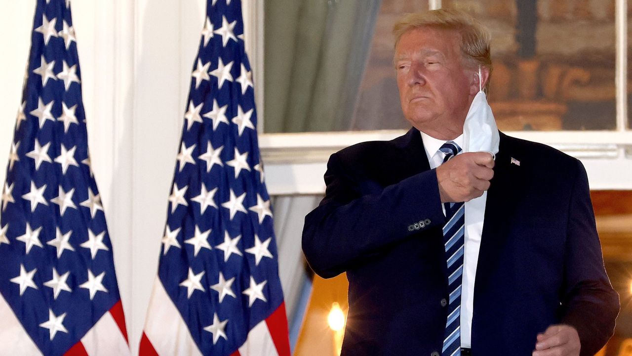 US President Donald Trump removes his mask on his return to the White House from Walter Reed National Military Medical Center, where he was treated for coronavirus.