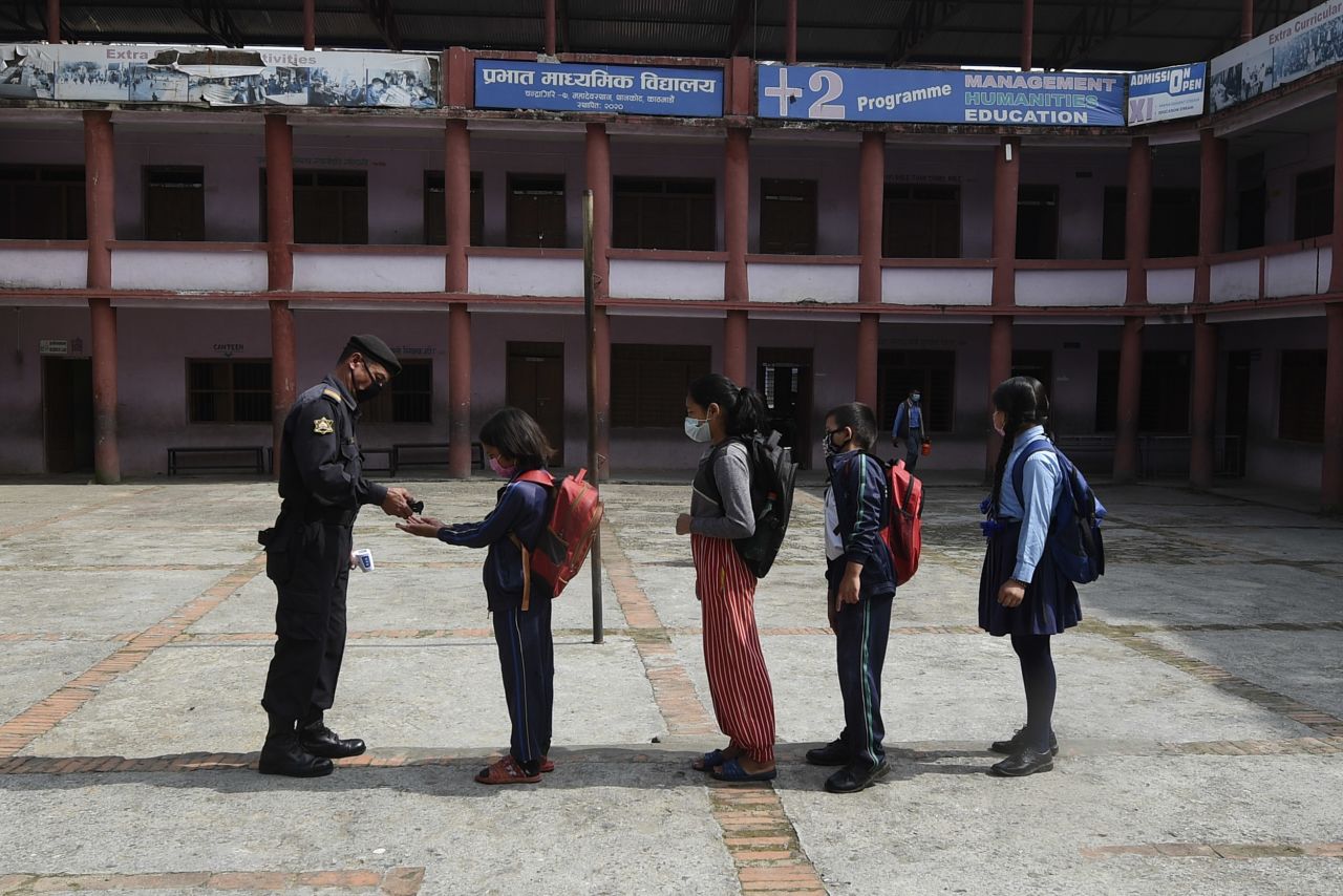 A security guard gives hand sanitizer to students as they arrive at the Prabhat secondary school on the outskirts of Kathmandu, Nepal, on October 6.