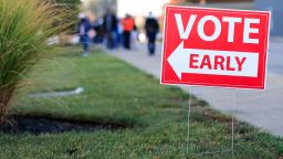 A sign for early voting is displayed as people wait in line at the Hamilton County Board of Elections to participate in early voting, Tuesday, Oct. 6, 2020, in Norwood, Ohio. (AP Photo/Aaron Doster)