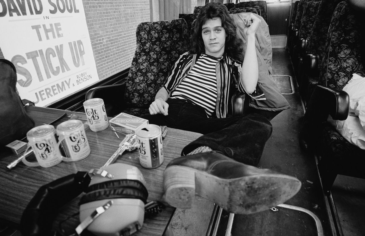 Eddie Van Halen sits in the band's tour bus outside the Lewisham Odeon on May 27, 1978. On the table are cans of Colt 45, matches and a replica hand gun.
