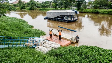Local workers haul away trash collected by the autonomous Interceptor 001 anchored in the Cengkareng Drain waterway in Jakarta, Indonesia.