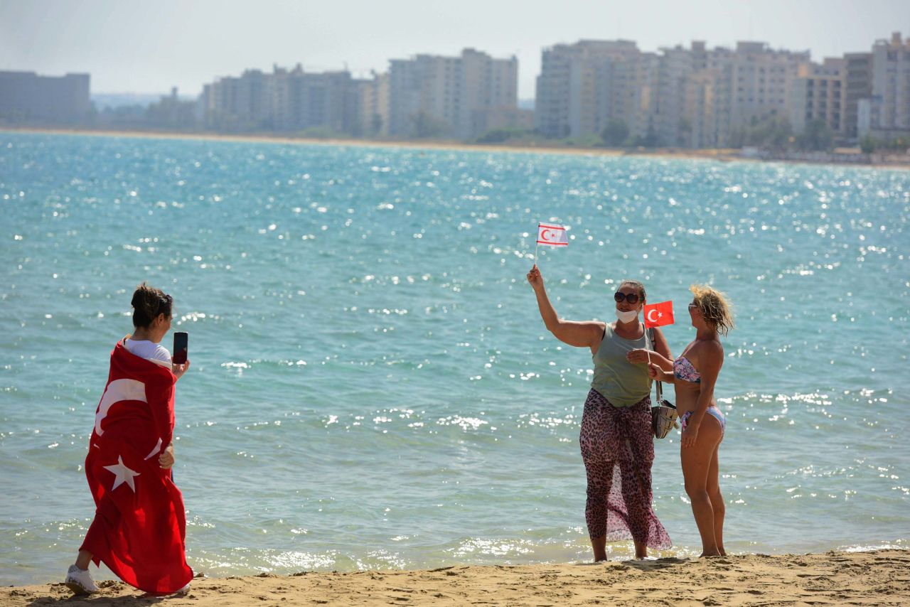 People with Turkish and Turkish Cypriot breakaway flags take photos of each other at the beach with abandoned buildings, in the background, after police opened the beachfront of Varosha on Thursday.
