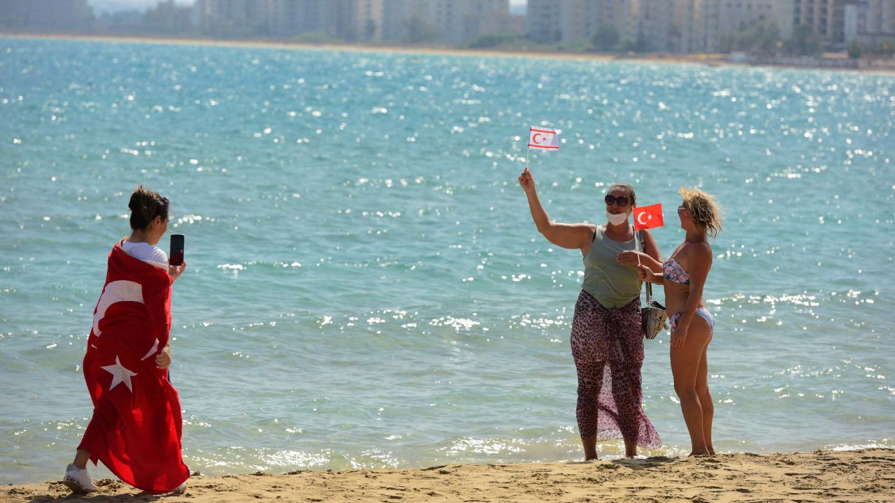 People with Turkish and Turkish Cypriot breakaway flags take photos of each other at the beach with abandoned buildings, in the background, after police opened the beachfront of Varosha on Thursday.