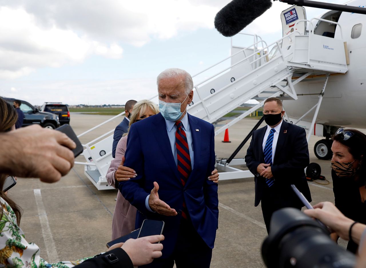 Biden is reminded by his wife, Jill, to maintain proper social distancing as he speaks to reporters at an airport in Miami on October 5.