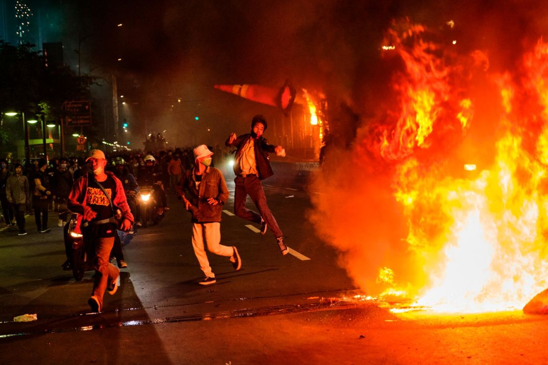 A protester throws a traffic cone onto a fire during Thursday in Jakarta.