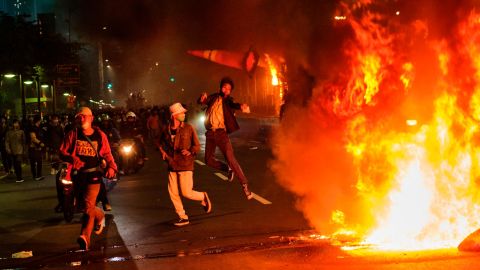 A protester throws a traffic cone onto a fire during Thursday in Jakarta.