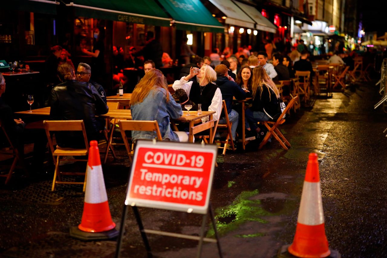 People drink outside at a cafe in Soho, in central London on September 23.