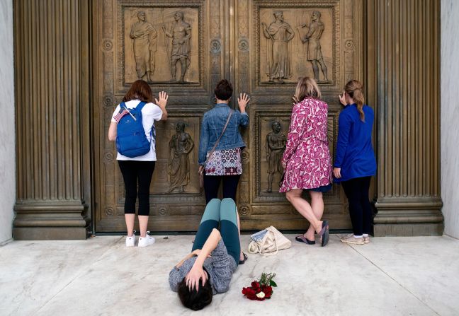 Conservative women who support Barrett's nomination pray while touching the Supreme Court's doors on September 26. Another woman lies on the ground nearby, mourning the death of <a  target="_blank">Justice Ruth Bader Ginsburg.</a>