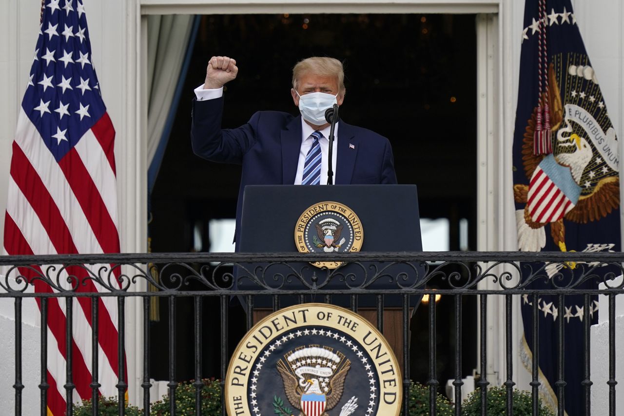 President Trump raises a fist as he arrives at the balcony of the White House to speak to a crowd of supporters. 