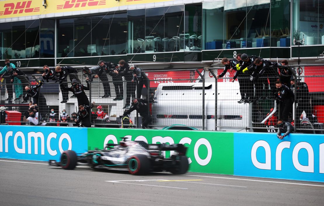 Mercedes team members celebrate on the pitwall as Lewis Hamilton of Great Britain crosses the line to win the Eifel GP to tie Michael Schumacher's F1 record of 91 victories.