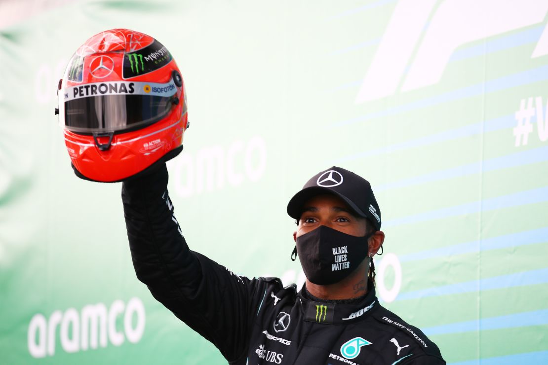 Lewis Hamilton holds aloft a helmet worn by Michael Schumacher after he tied the German legend's F1 win record at the Eifel GP.