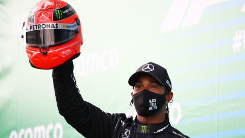 Lewis Hamilton holds aloft a helmet worn by Michael Schumacher after he tied the German legend's F1 win record at the Eifel GP.