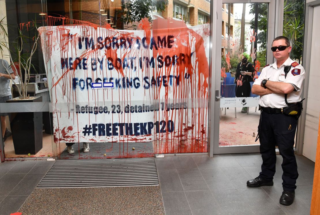 A security guard stands by a door smeared with fake blood and tomatoes by protesters at the University of Queensland. 