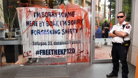 A security guard stands by a door smeared with fake blood and tomatoes by protesters at the University of Queensland.