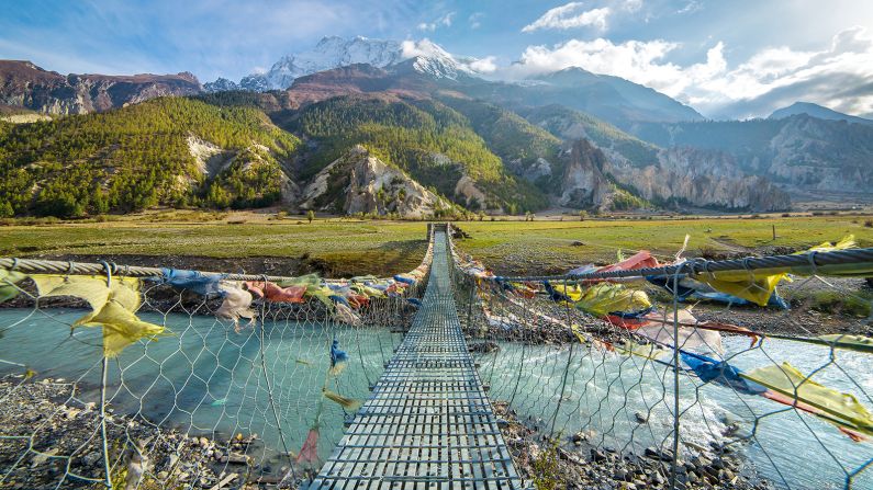 <strong>10. Annapurna Circuit, Nepal:</strong> Lonely Planet's new edition of its Ultimate Travel List includes many a must-visit destination, including Nepal's Annapurna Circuit. Hiking this terrain, you'll pass through rice paddies, yak grasslands and a snowy mountain pass. Pictured here: a suspension bridge with Buddhist prayer flags.