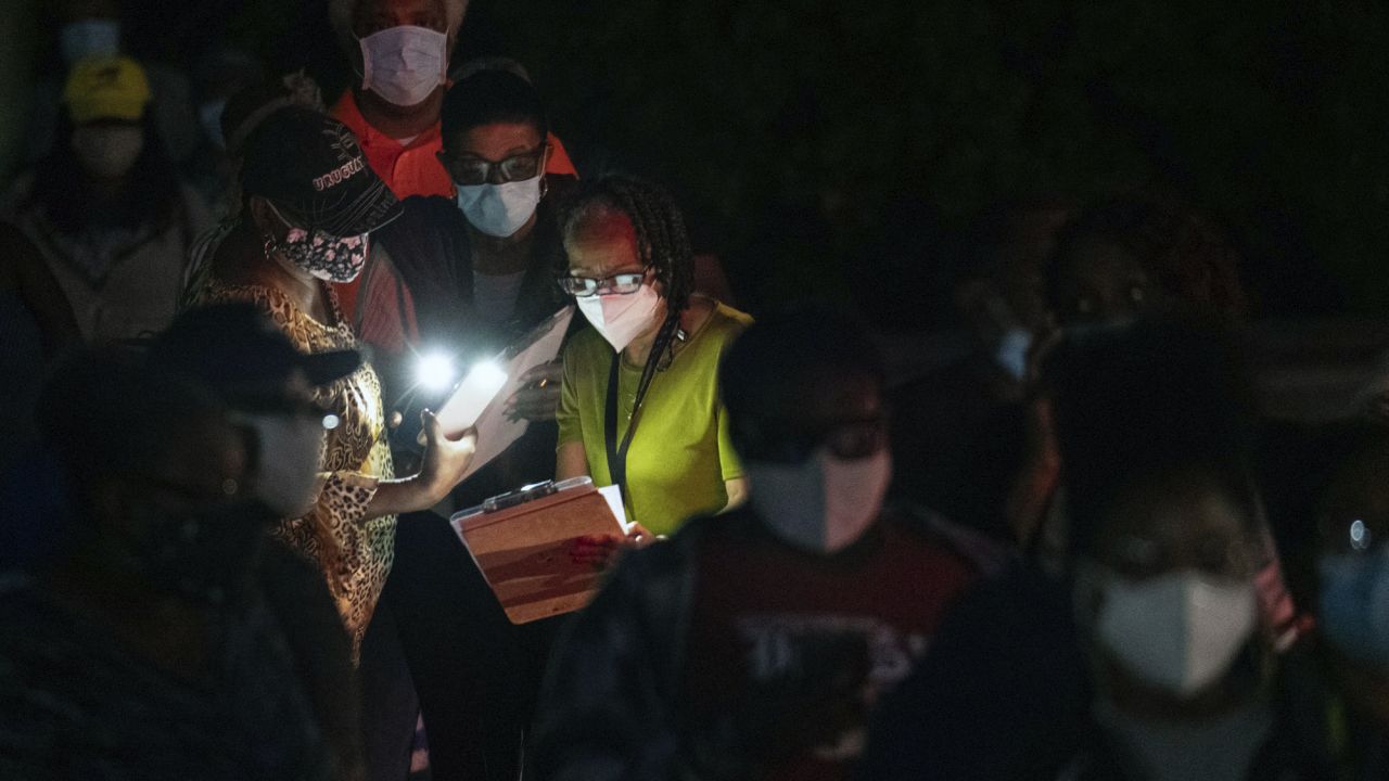 A group of women share the light from their phones as they fill out pre-registration forms while in line for early voting this month in Decatur, Georgia.