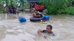 A soldier (front) holds on to a rope as a woman is is pulled to safety through flood waters in a village in Cambodia's western Battambang province on October 10, 2020, following heavy rains in the region.