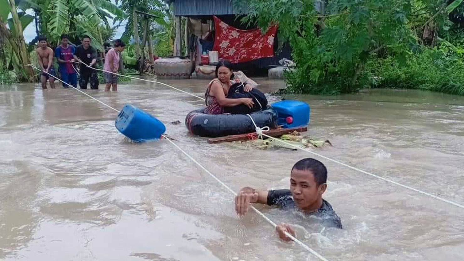 A soldier (front) holds onto a rope as a woman (C) is is pulled to safety through flood waters in a village in Cambodia's western Battambang province on October 10, 2020, following heavy rains in the region. (Photo by STR / AFP) (Photo by STR/AFP via Getty Images)