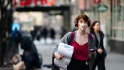 NEW YORK, NY - MARCH 13: A woman wearing a protective mask carries a toilet paper package on the street on March 13, 2020 in New York City.  City. (Photo by Jeenah Moon/Getty Images)