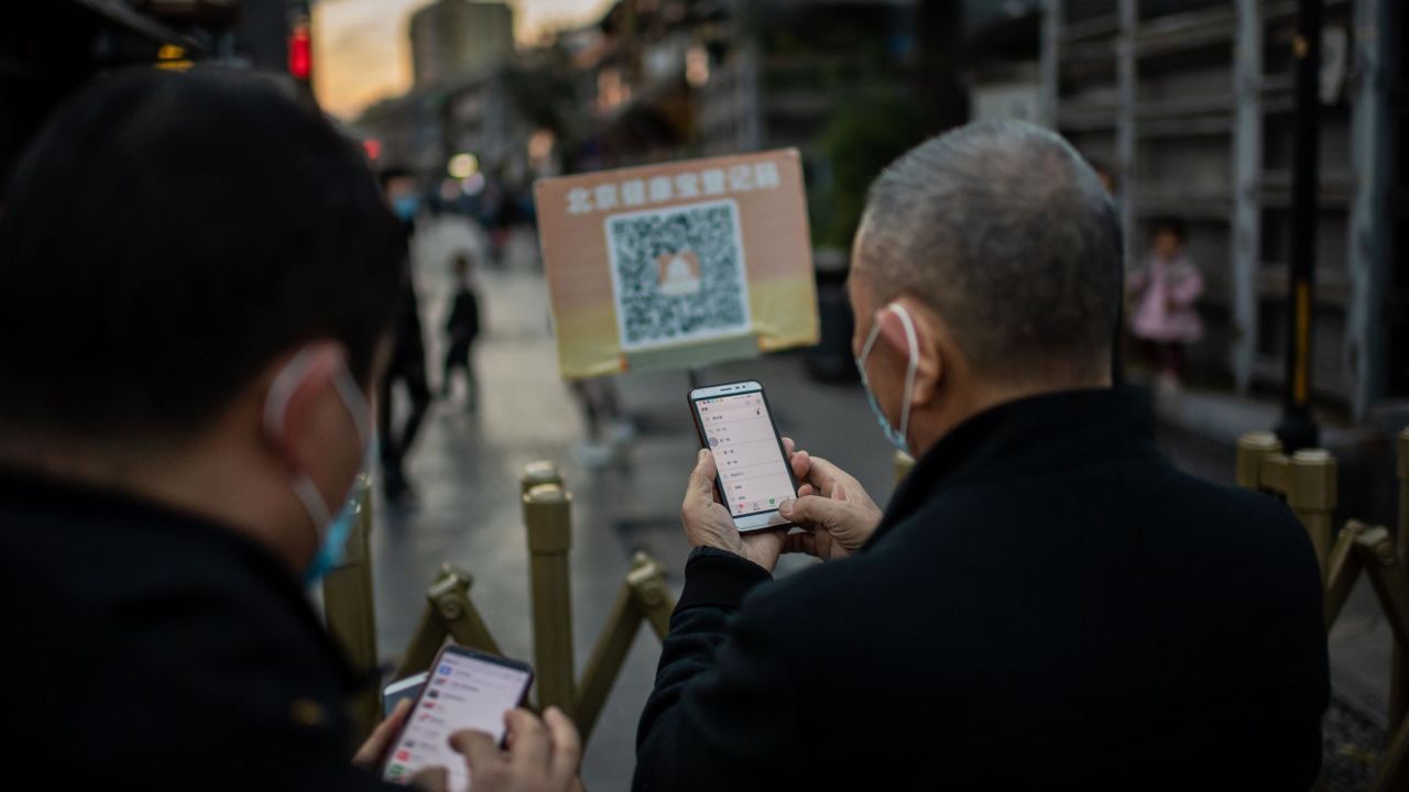 People wearing face masks scan a QR code with their smartphones to check their "Health Kit" to enter an area in Beijing this week.