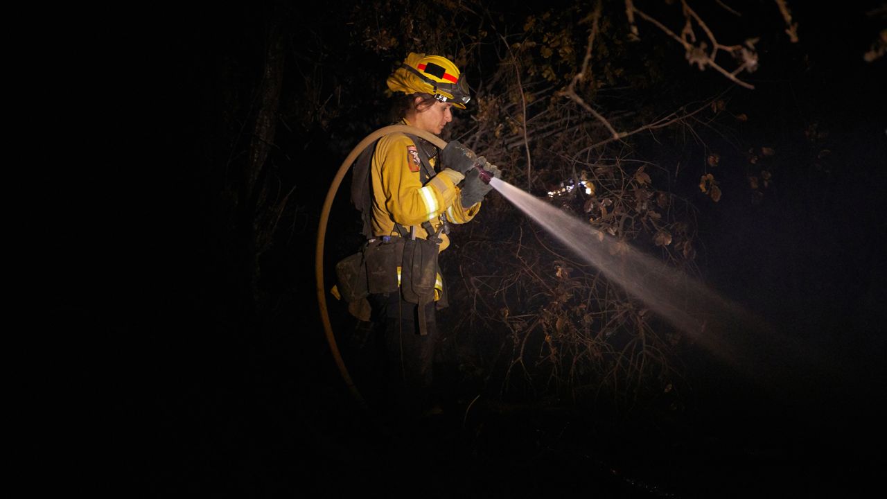 A fire fighter puts out hot spots from the Zogg Fire in Igo.