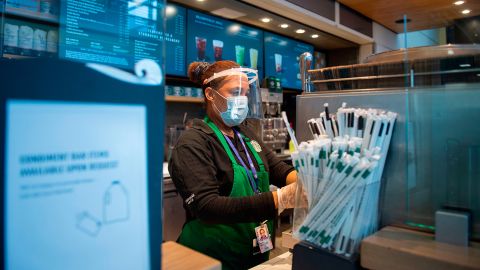 A Starbucks employee wears a face shield and mask as she makes a coffee in Ronald Reagan Washington National Airport in Arlington, Virginia.