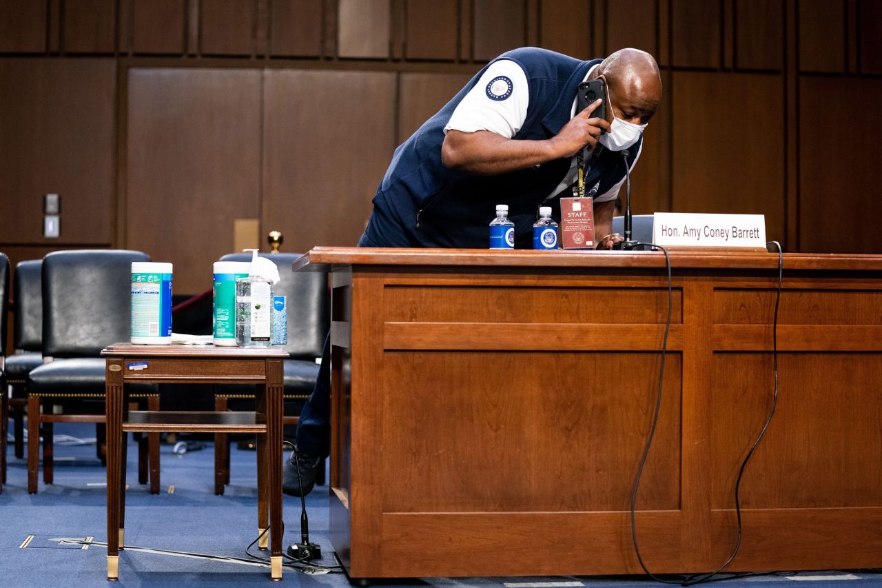 A staffer adjusts Barrett's microphone on October 14. There were technical difficulties with the hearing room's audio system, causing a couple of delays.