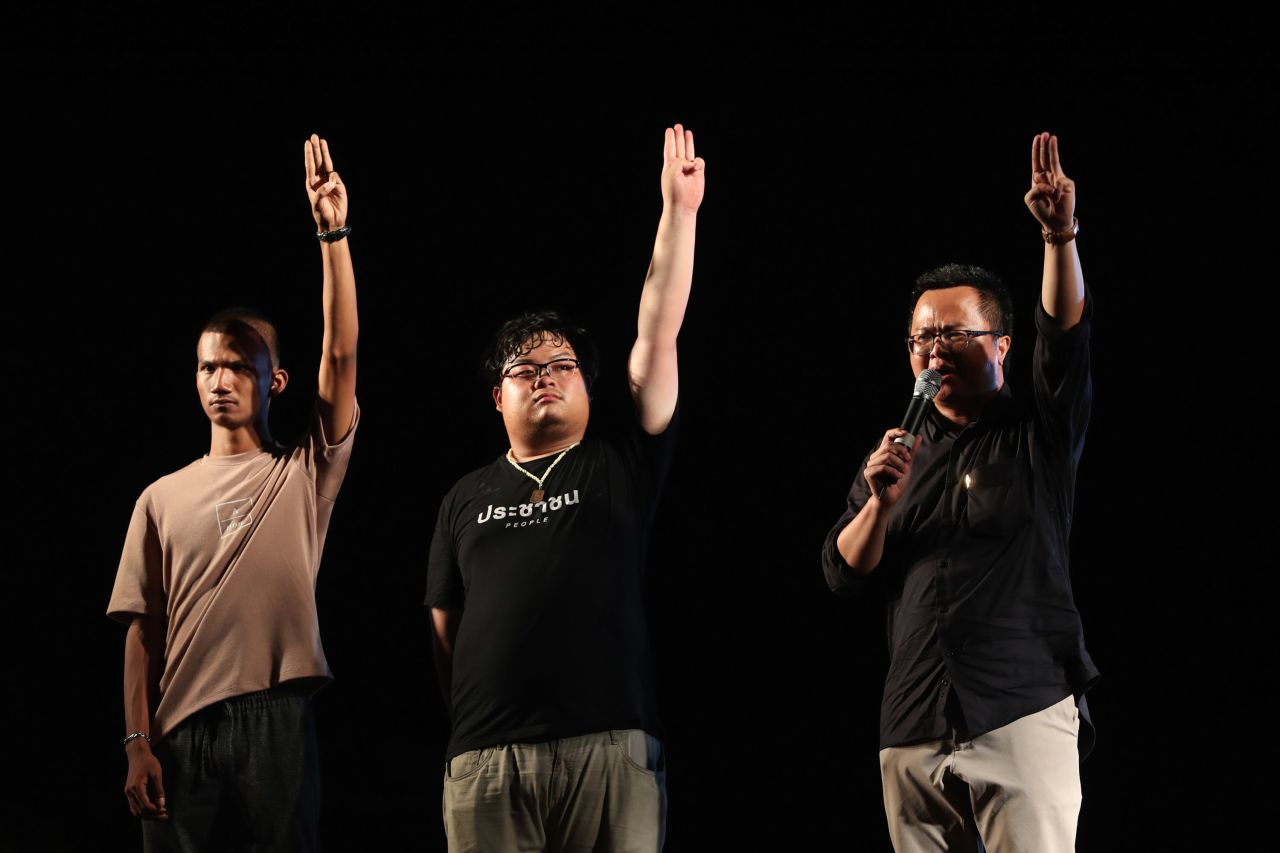 Activists for democracy, from left, Panupong Jadnok, Arnon Nampha, and Parit Chiwarak, raise three-finger salutes on October 15.