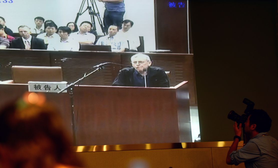 Journalists follow the progress on a television screen of the trial of British investigator Peter Humphrey (center) linked to beleaguered pharmaceutical giant GSK and his wife, at the Shanghai Intermediate Court on August 8, 2014.