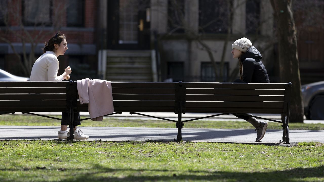 Two women practice social distancing while talking on Commonwealth Avenue Mall, April 4, in Boston. The term "social distancing" has become a commonly used term this year amid the Covid-19 pandemic.