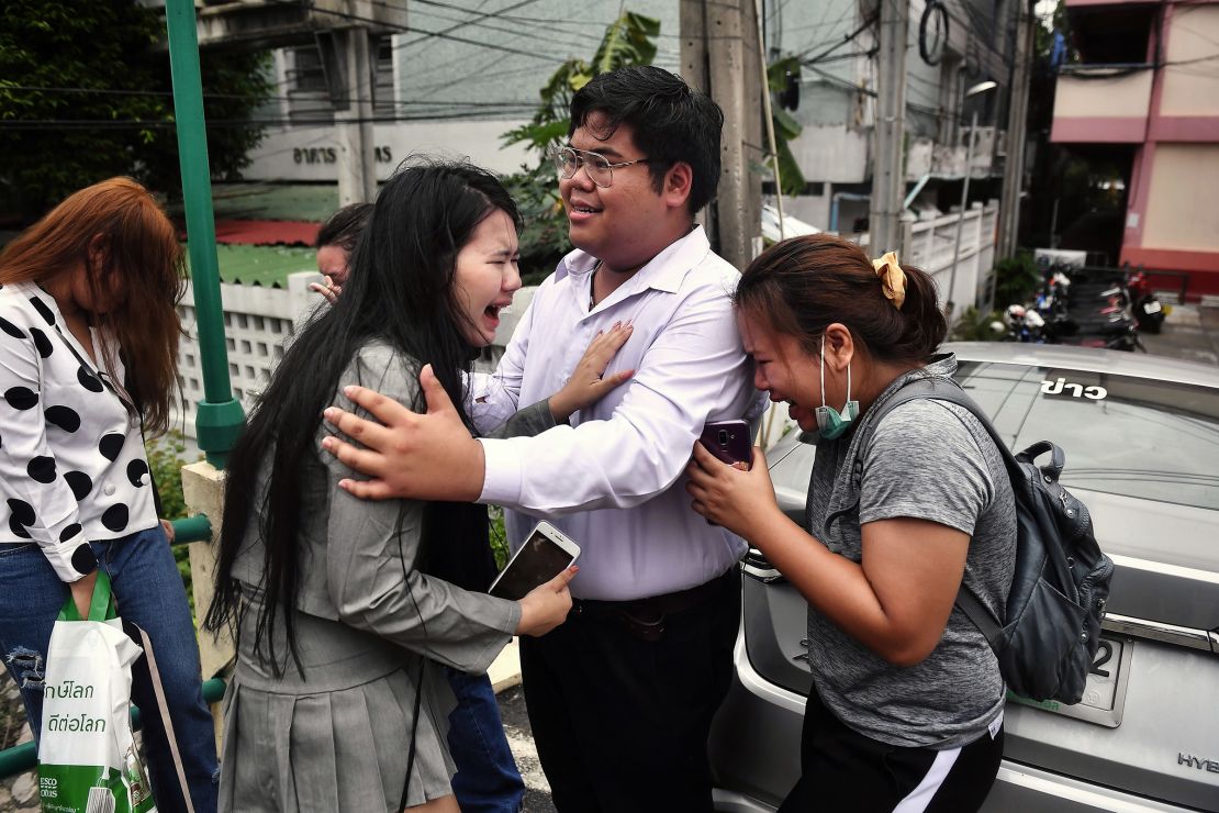Pro-democracy activist Bunkueanun "Francis" Paothong comforts loved ones before he enters the Dusit police station to answer charges of harming Thailand's Queen Suthida on October 16, 2020. 