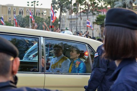 Thailand's Queen Suthida, center, and Prince Dipangkorn Rasmijoti, center-left, ride inside a royal motorcade as it drives past a pro-democracy rally on October 14.