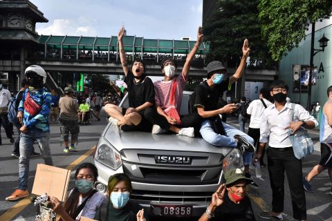 Pro-democracy sitting atop a police vehicle give the three-finger salute, a reference to the Hunger Games movies, which has become a popular symbol of the protests.
