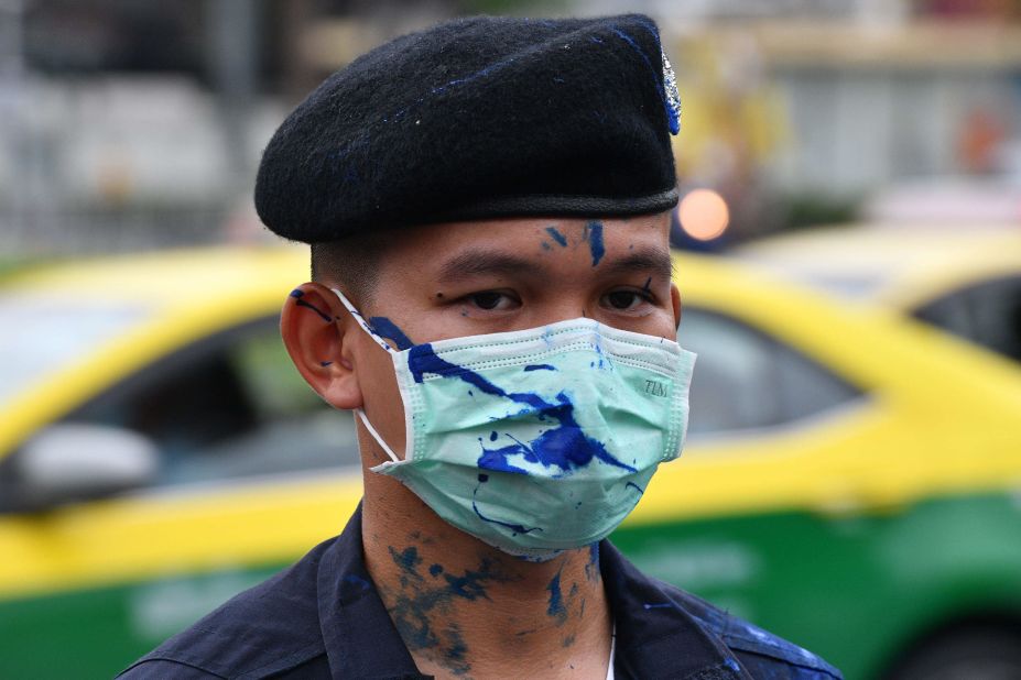 Blue paint, thrown during a demonstration by pro-democracy protesters, is seen splattered on a policeman, as he stand guards while waiting for the royal motorcade to pass, in Bangkok on October 13.