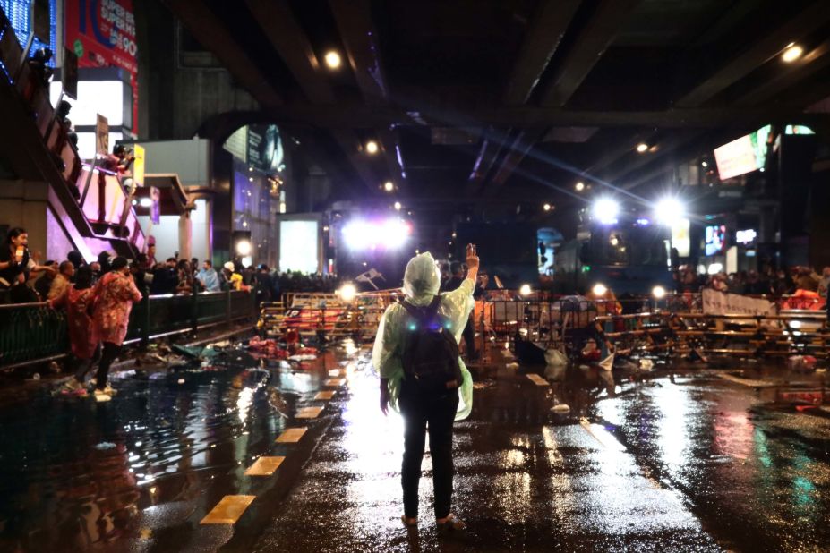 A pro-democracy protester gives the three-finger salute after police fired water cannons during an anti-government rally .