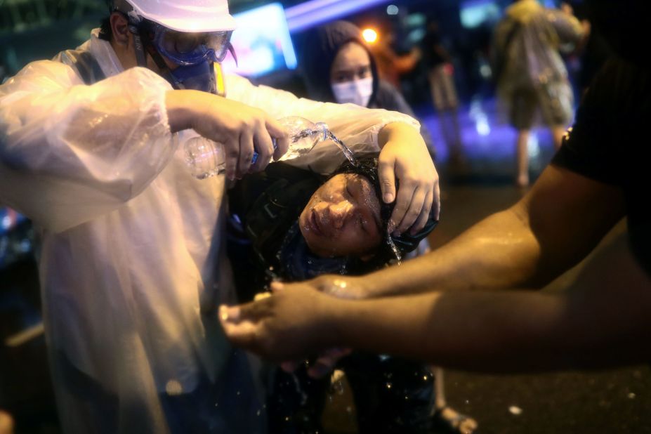 Protesters gather around a fellow pro-democracy activist to wash his face after police fired water cannons laced with pepper on October 16.