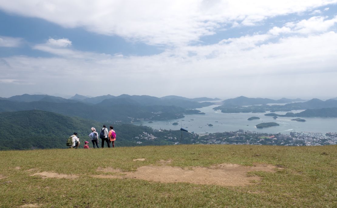 People pose for photos at a viewpoint overlooking Sai Kung in Hong Kong's Ma On Shan Country Park on October 16, 2020.
