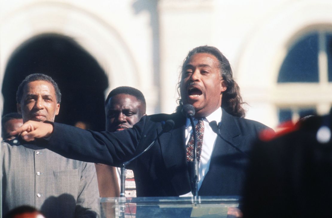 Reverend Al Sharpton speaks to the crowd while a member of the Nation of Islam stands guard at the Million Man March October 16, 1995 in Washington, DC. 