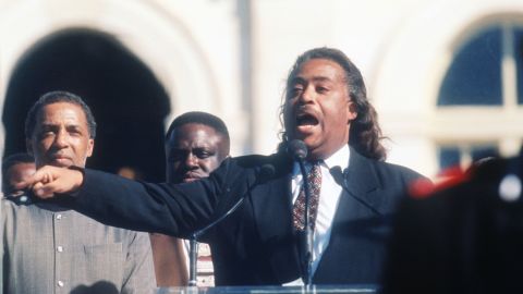 Reverend Al Sharpton speaks to the crowd while a member of the Nation of Islam stands guard at the Million Man March October 16, 1995 in Washington, DC. 