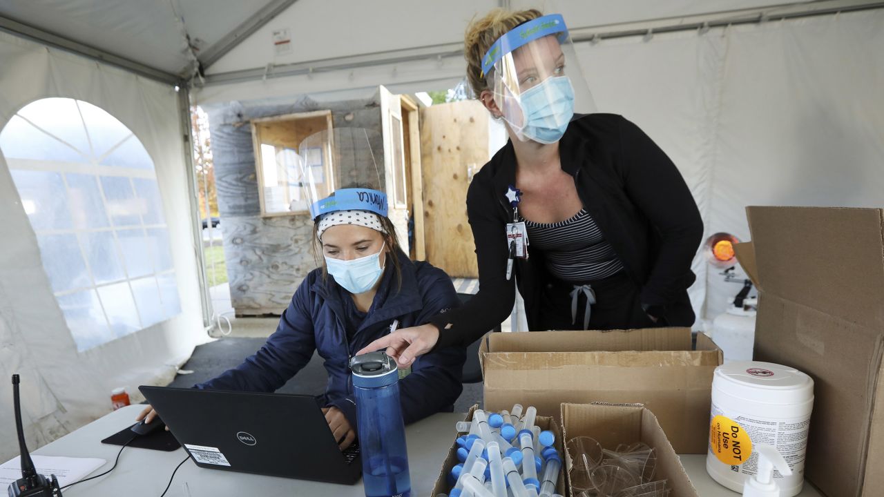 Nursing assistant Monica Brodsky, left, and nurse Taylor Mathisen work at a drive-thru testing site for COVID-19 in the parking lot at UW Health Administrative Office Building in Middleton, Wis., Monday, Oct. 5, 2020. A surge of coronavirus cases in Wisconsin and the Dakotas is forcing a scramble for hospital beds and raising political tensions, as the Upper Midwest and Plains emerge as one of the nation's most troubling hotspots. (Amber Arnold/Wisconsin State Journal via AP)