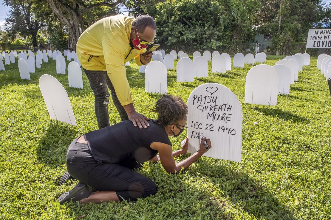 Rachel Moore honors her mother, Patsy Gilreath Moore, by writing her mother's name on a symbolic tombstone at Simonhoff Park in the Liberty City neighborhood of Miami on October 14.