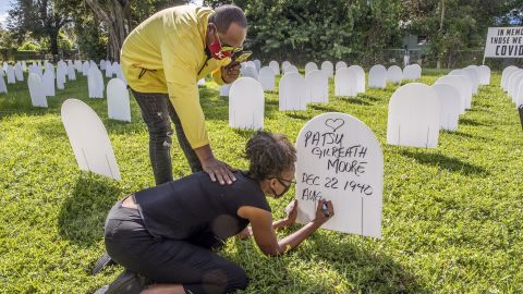 Rachel Moore honors her mother, Patsy Gilreath Moore, by writing her mother's name on a symbolic tombstone at Simonhoff Park in the Liberty City neighborhood of Miami on October 14.