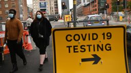 Pedestrians wearing protective face coverings walk past a Covid-19 testing sign in Manchester in north-west England on October 17, 2020, as further restrictions come into force as the number of novel coronavirus COVID-19 cases rises. - About 28 million people in England, more than half the population, are now living under tough restrictions imposed on Saturday as the country battles a surge in coronavirus cases. (Photo by Oli SCARFF / AFP) (Photo by OLI SCARFF/AFP via Getty Images)