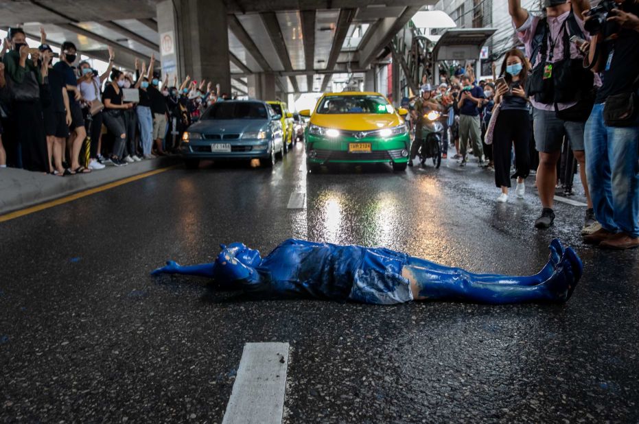 A protester covered in blue paint lies on a road during a protest in Udom Suk, in Bangkok's suburbs, on October 17. 